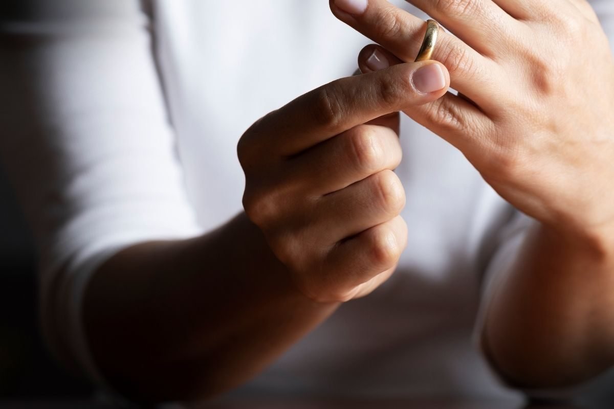 Como se Preparar para um Divórcio: mão de uma pessoa retirando aliança de casamento, simbolizando o início do processo de divórcio no contexto do Direito de Família.