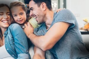 A Evolução do Direito de Família: Pai, mãe e filha abraçados e rindo juntos em casa, exemplificando a felicidade e segurança proporcionadas pelas leis de união estável no Brasil.