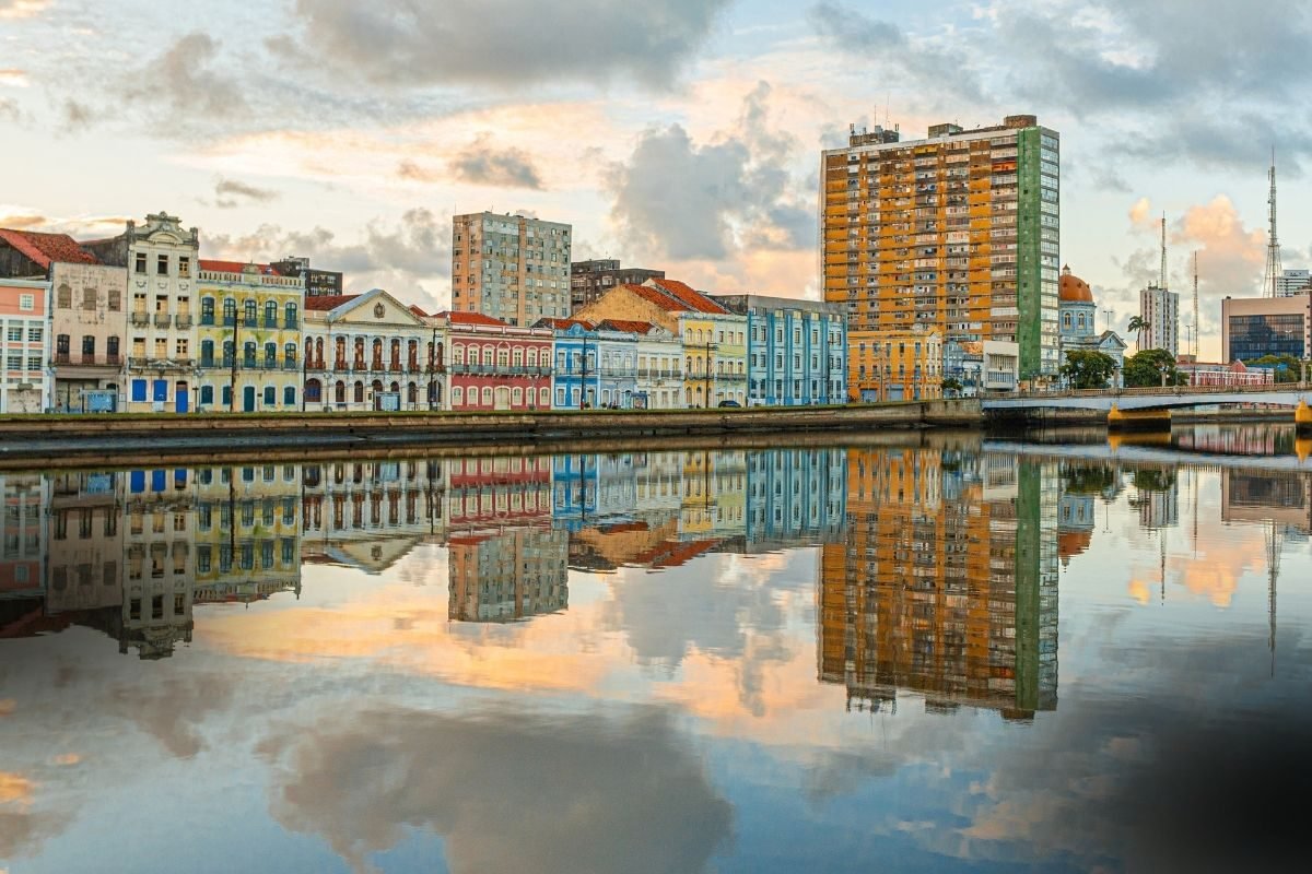 Consulta Advogado de Família em Recife: reflexo pitoresco da arquitetura colorida e diversificada da cidade na água ao entardecer.