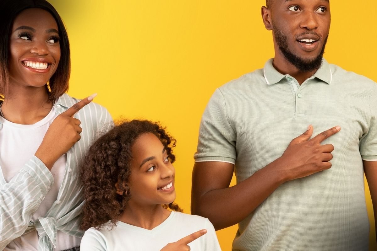 O Que é Direito de Família? Uma família afro-americana sorridente composta por mãe, pai e filha apontando para o lado direito, representando a união e os aspectos legais do direito de família.